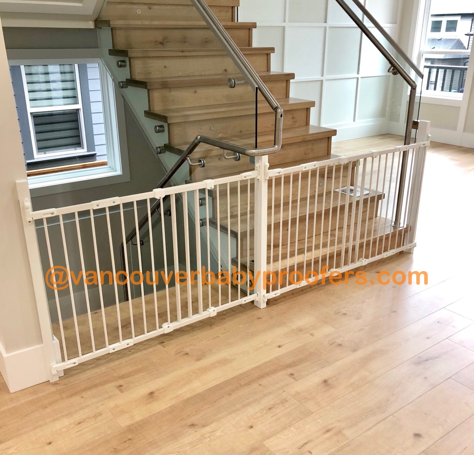 White safety gate custom-fitted to a glass-railing staircase in a Vancouver home