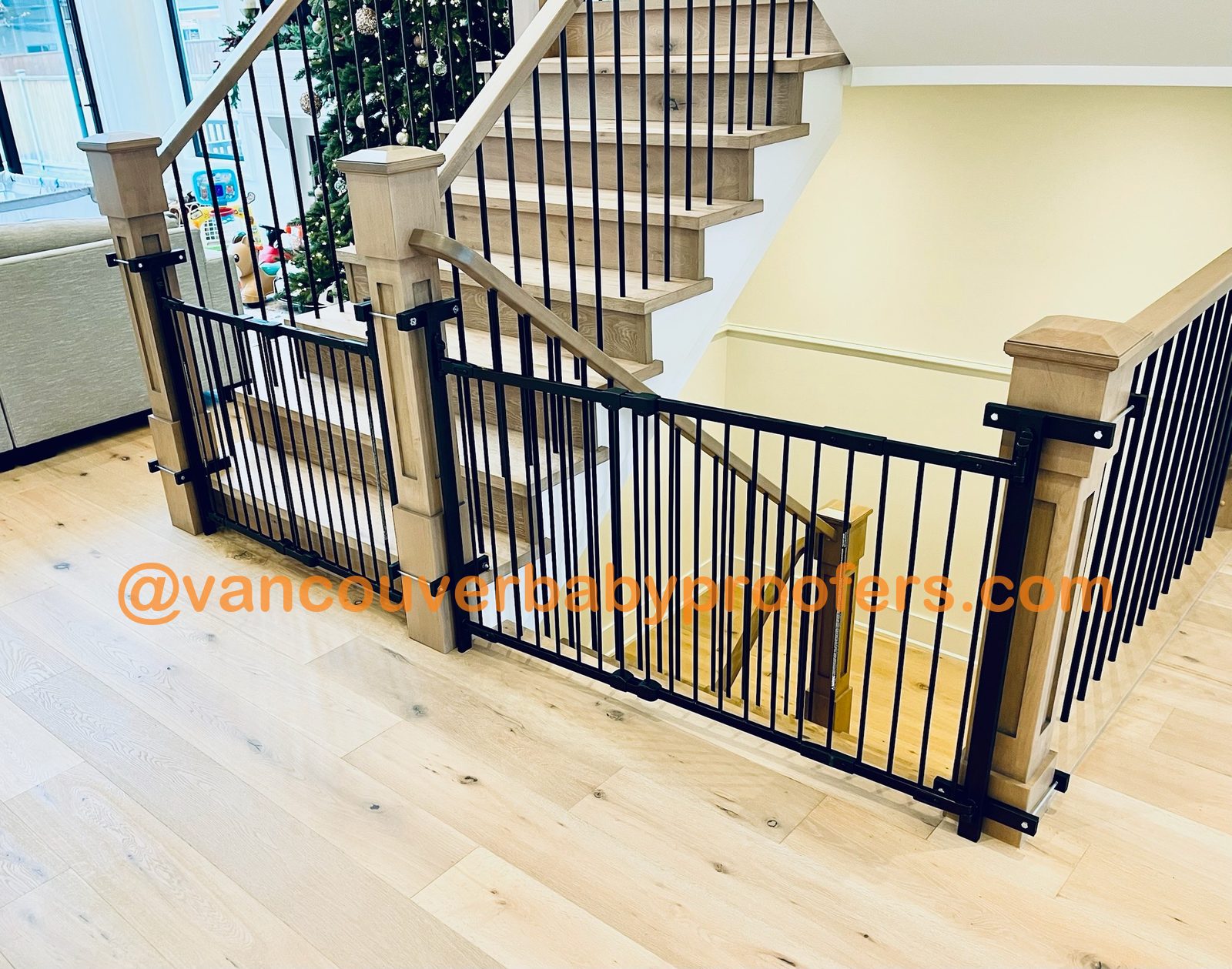 Two safety gates secured to wooden staircase posts with the no-hole clamp system, no drilling into the posts